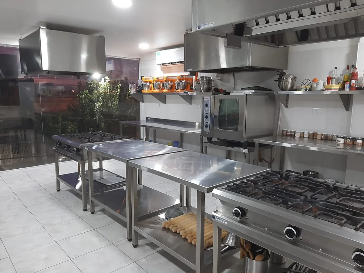 Cocina profesional equipada de una sede de IGI, con mesadas de acero, hornos y anafes